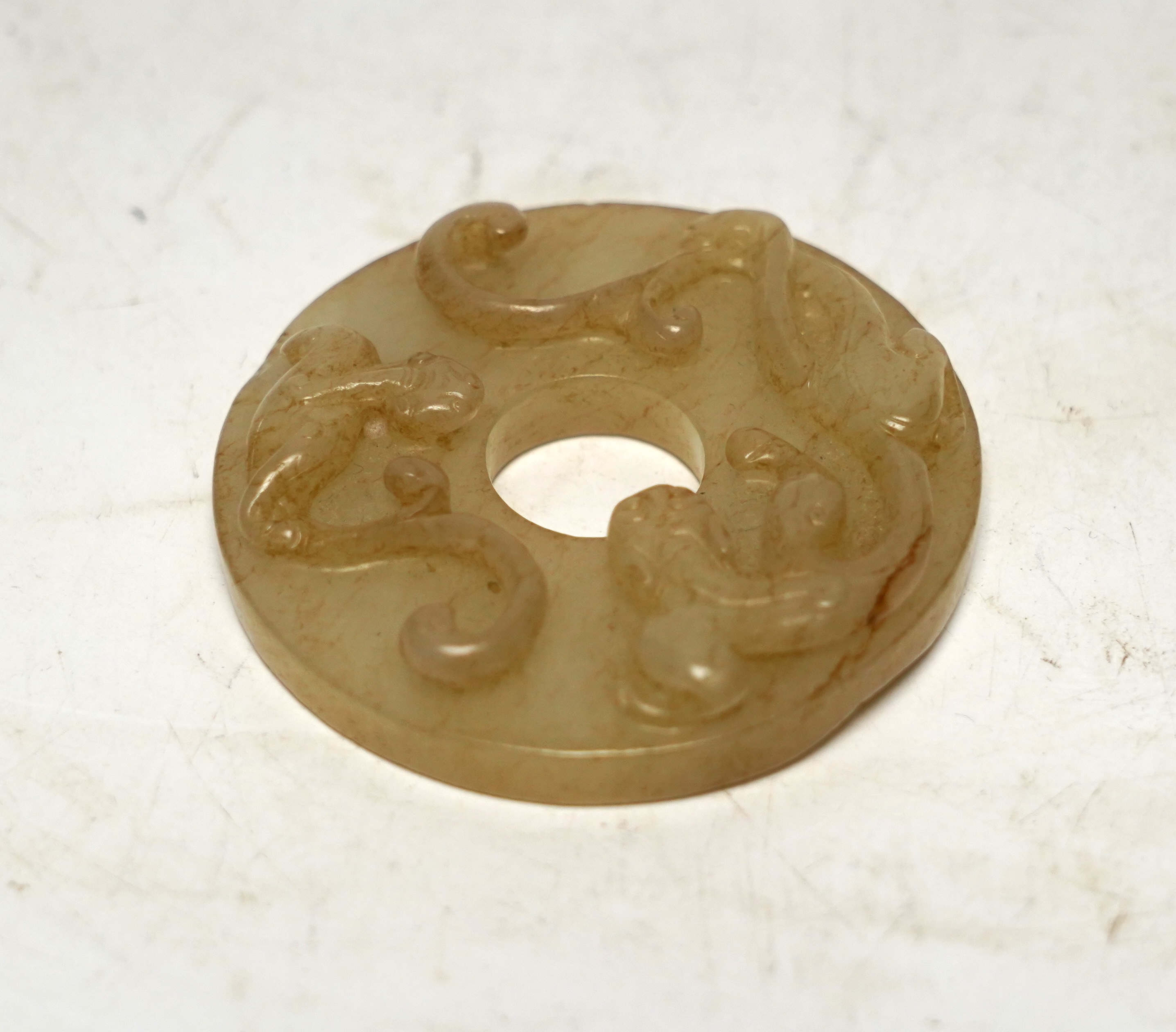 An 18th century Chinese mottled jade bi disc, decorated with two carved chilong, 5.8cm diameter